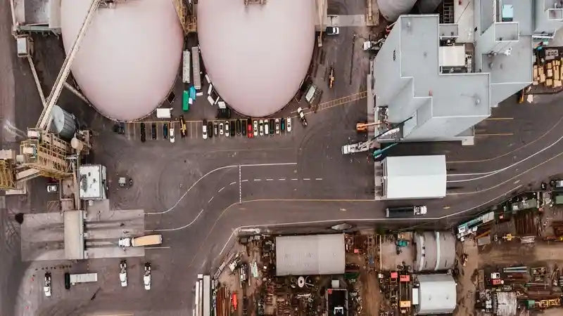An aerial view of a sprawling industrial complex, featuring large storage tanks likely used for refrigerants like R-410A, R-134A, and R-404A, indicating operations related to HVAC and chemical processing. The complex includes various buildings, parking areas with vehicles, and what appears to be manufacturing or distribution facilities for refrigerants.